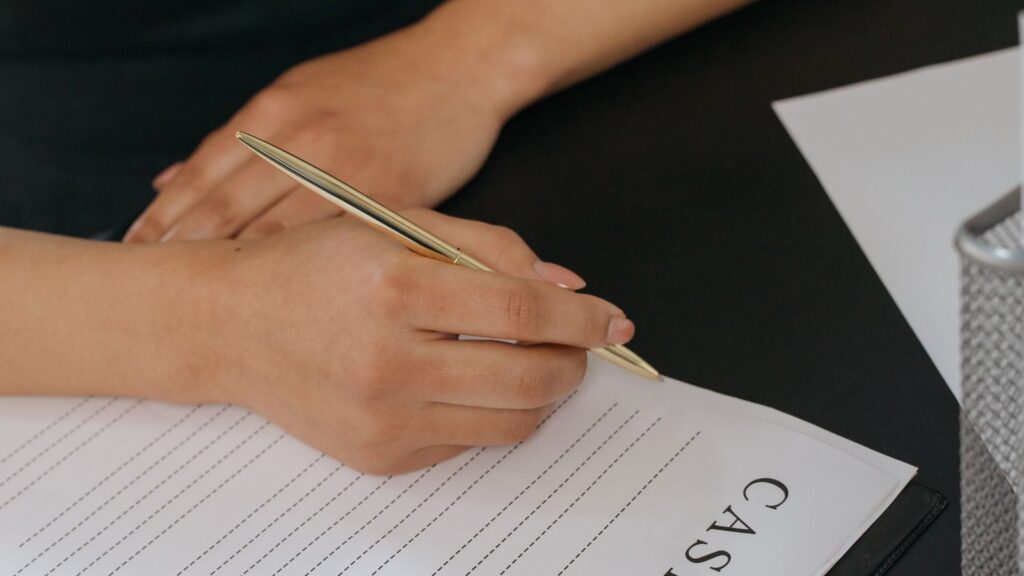 Main tenant un stylo et remplissant un document administratif sur un bureau