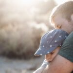 Père tenant tendrement son bébé dans ses bras en plein air