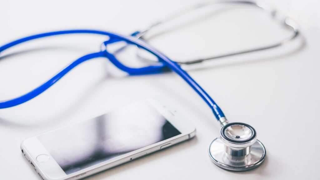 Stéthoscope posé à côté d'un smartphone sur une surface blanche