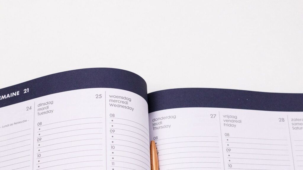 Agenda ouvert sur un planning hebdomadaire avec un stylo doré